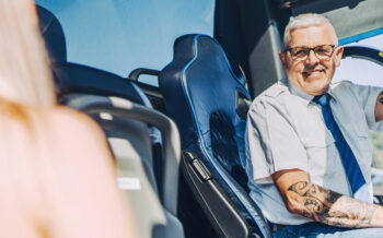 Busfahrer sitzt lächelnd am Steuer