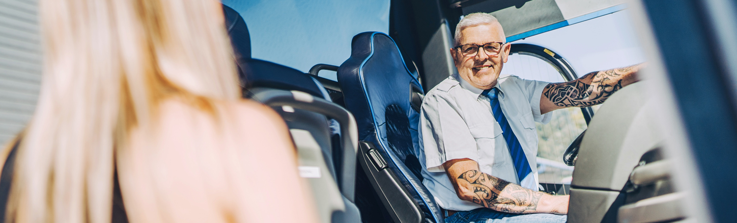 Busfahrer sitzt lächelnd am Steuer