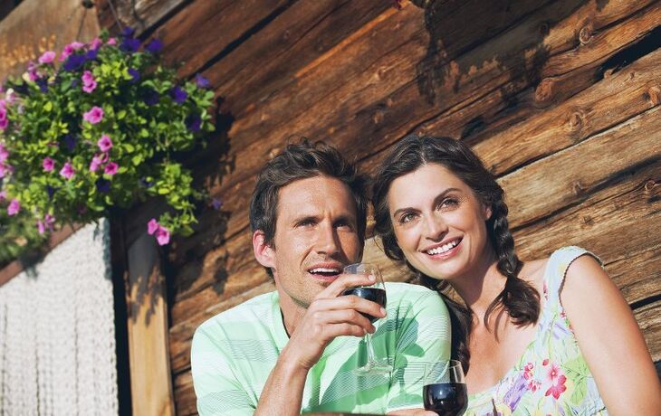 © tunedin - Fotolia - Italien,Südtirol,Paar vor der Blockhütte halten Weingläser,Lächeln,Portrait