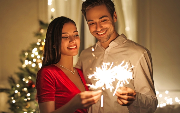 Schöne Paare, die den Silvesterabend mit Funken und glänzenden Feuerwerken feiern - © merla - stock.adobe.com