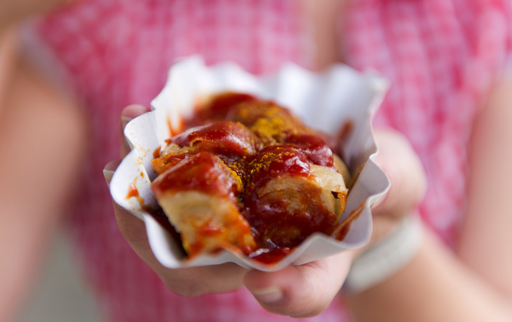 visitBerlin/Foto: Philip Koschel - Imbiss mit Currywurst in der Hand