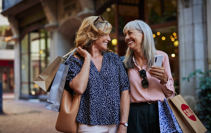 reife Frauen, die gemeinsam einkaufen gehen und sich dabei anschauen - © Rido - stock.adobe.com