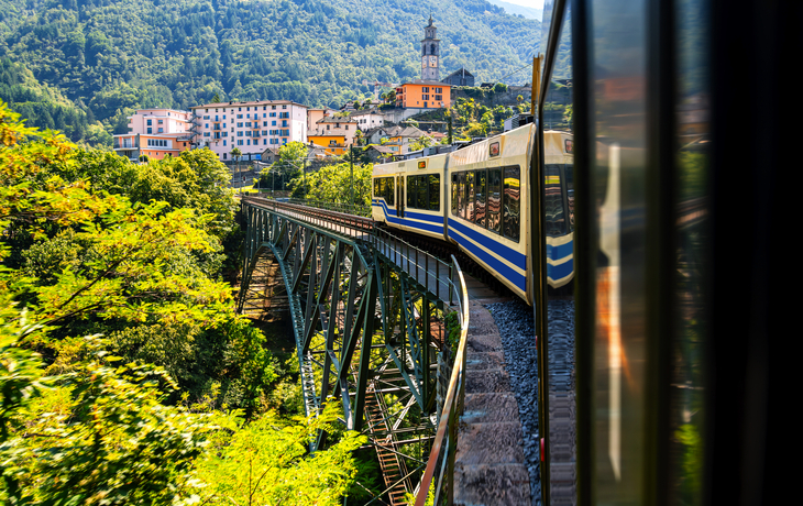 © ON-Photography - stock.adobe.com - Blick aus einem Waggon der Centovalli-Bahn auf der historischen Talbrücke aus Stahl in Intragna