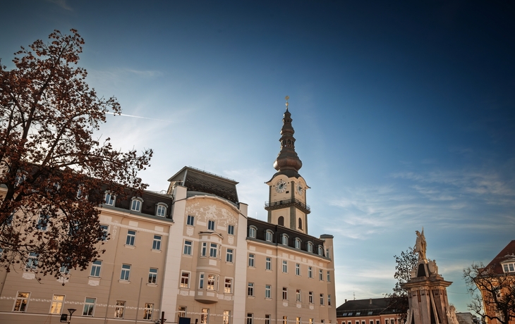 Stadtansicht mit historischen Gebäuden, roten Dächern und Bergen im Hintergrund. - © Silvia Eder - stock.adobe.com