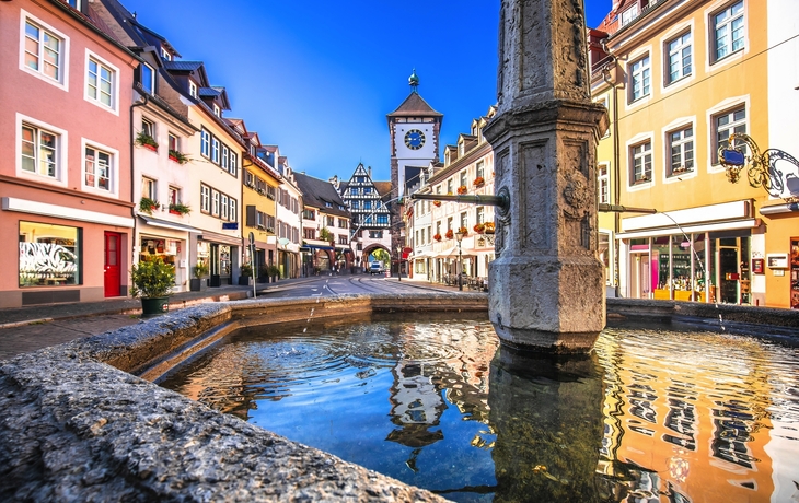 Blick auf bunte Gebäude und Marktplatz in einer Altstadt, umgeben von Hügeln. - © JFL Photography - stock.adobe.com