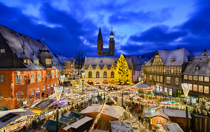 Winterlicher Weihnachtsmarkt mit festlich beleuchteten Buden und geschmücktem Baum. - ©Mapics - stock.adobe.com