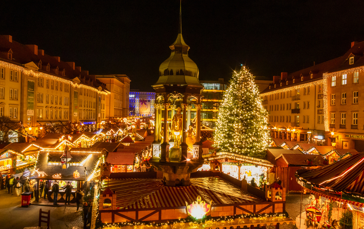 Weihnachtsmarkt mit beleuchteten Ständen und Besuchern in der Dämmerung. - © Horst Schmidt - stock.adobe.com