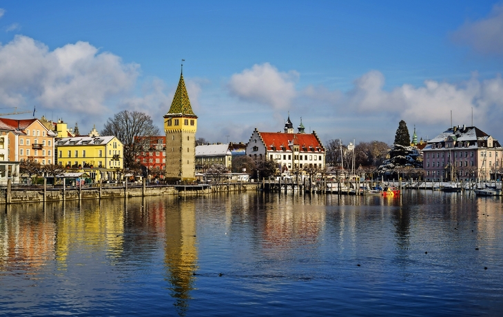 Nachtszene eines beleuchteten Weihnachtsmarktes mit Turm und Baumlichtern. - © hochfeld - stock.adobe.com