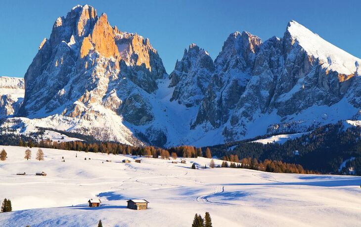 Verschneite Hütten in einer winterlichen Berglandschaft mit Tannenbäumen und strahlend blauem Himmel. - © Andrew Mayovskyy - stock.adobe.com