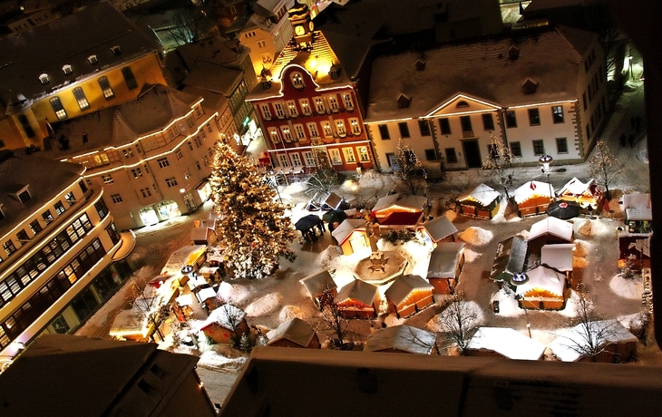 Blick auf einen weihnachtlich erleuchteten Marktplatz mit geschmücktem Baum von oben.