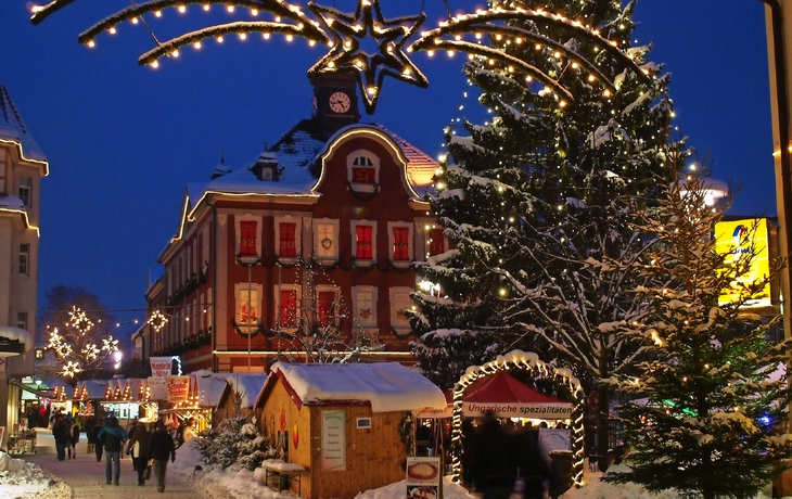 Blick auf einen weihnachtlich erleuchteten Marktplatz mit geschmücktem Baum von oben.