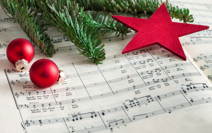 Notenblätter mit roten Christbaumkugeln, Zweigen und Stern. - ©eyetronic - stock.adobe.com