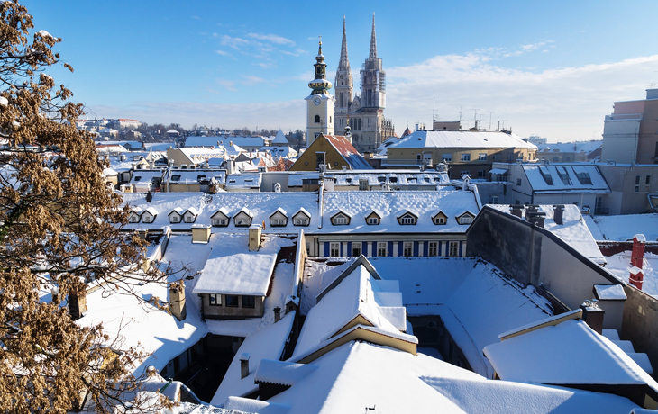 Stadtansicht mit Kathedrale und schneebedeckten Dächern unter blauem Himmel. - © ilijaa - stock.adobe.com