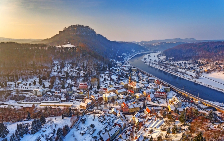Dorf im Winter von oben, mit Fluss und bewaldeten Hügeln im Hintergrund. - © Sliver - stock.adobe.com