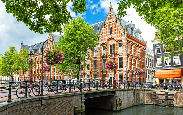 Kanalanlage in Amsterdam mit bunten Blumen und traditionellen Häusern im Hintergrund. - © Nikolay N. Antonov - stock.adobe.com
