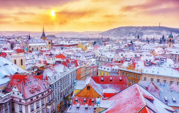 Verschneite Stadtansicht mit Fluss und Brücke, im Hintergrund eine Burg. - © Michaela Jílková - stock.adobe.com