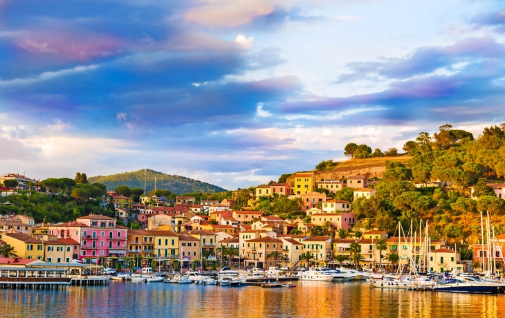 Bunte Häuser und Boote am Hafen vor einer hügeligen Landschaft - © e55evu - stock.adobe.com