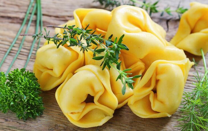Einige rohe Tortellini mit frischen Kräutern auf einem Holztisch. - © quipu - Fotolia