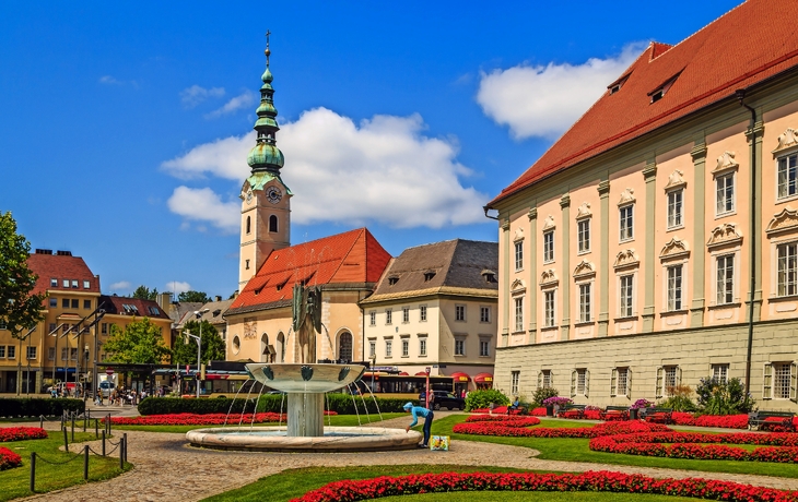 Steinstatue eines Drachen und eines Mannes vor historischer Gebäudekulisse. - © EKH-Pictures - stock.adobe.com