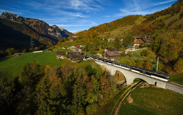 Alpenstraße mit traditionellen Holzhäusern und Kirche bei sonnigem Wetter - © Bogdan Lazar - stock.adobe.com