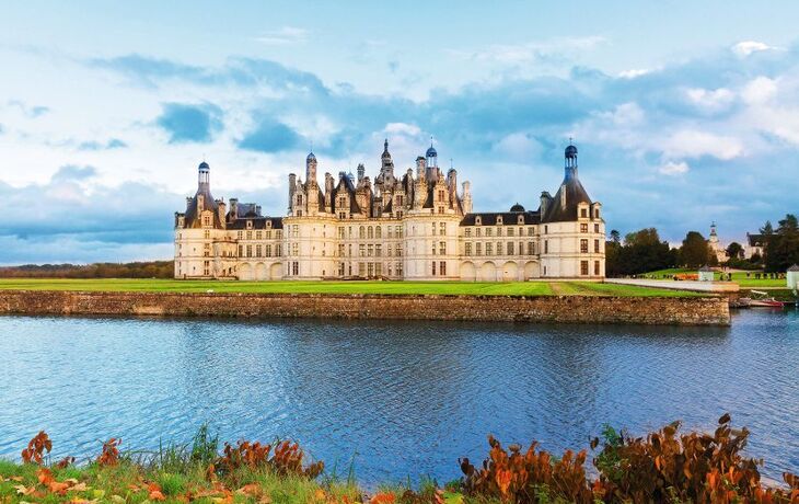 Schloss am Ufer eines Flusses unter blauem Himmel mit Wolken. - © neirfy - Fotolia