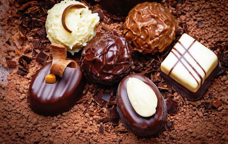 Verschiedene Pralinen auf einer Schicht aus Kakaopulver und Schokoladenraspeln. - © Vera Kuttelvaserova - Fotolia