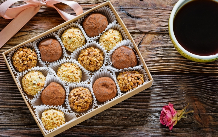 Verschiedene Pralinen auf einer Schicht aus Kakaopulver und Schokoladenraspeln. - © Vera Kuttelvaserova - Fotolia