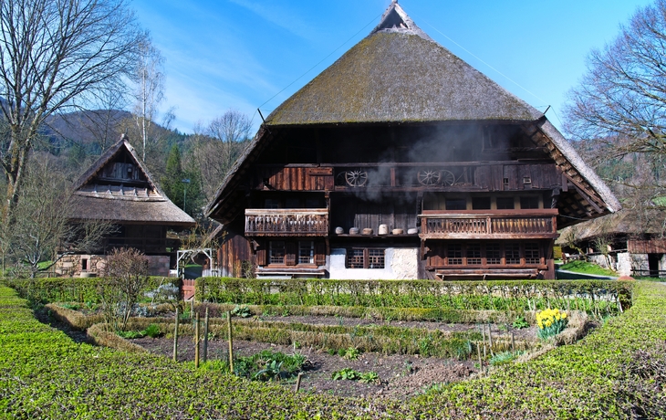 Fachwerkhaus mit Strohdach und Garten im Vordergrund.
