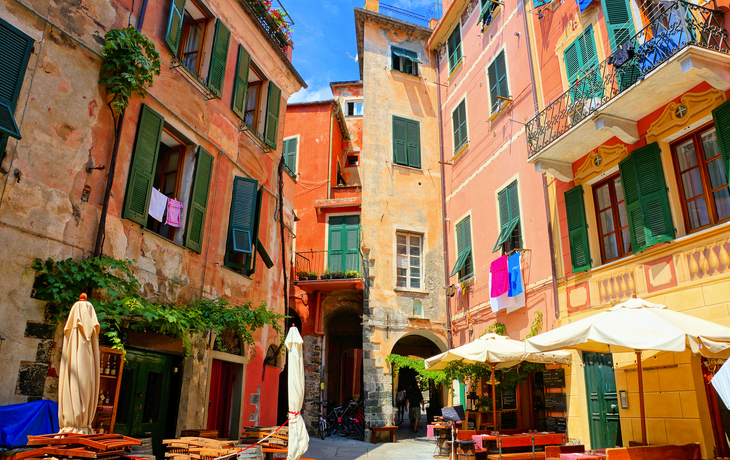 Bunte Häuser von Riomaggiore an der felsigen Küste Italiens unter blauem Himmel. - ©Warpedgalerie - stock.adobe.com