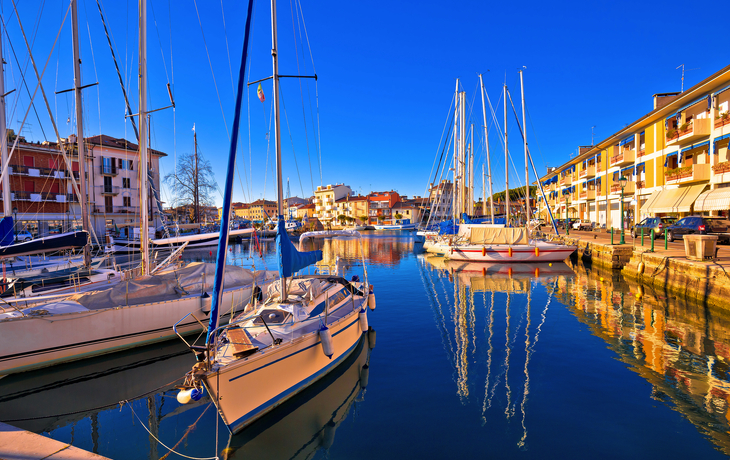 Segelboote im Hafen, sonniger Tag, ruhiges Wasser, Gebäude im Hintergrund entlang des Kais. - ©xbrchx - stock.adobe.com