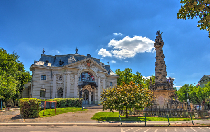 Platz mit Statue, barocker Kirche und Gebäuden unter blauem Himmel. - © mehdi33300 - stock.adobe.com
