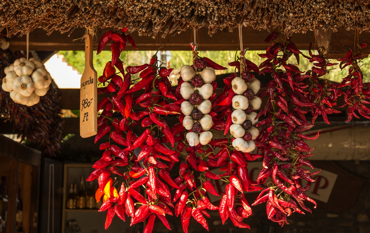 Bunte Chilischoten und Knoblauch an einem Marktstand. - © Neil Julian - stock.adobe.com