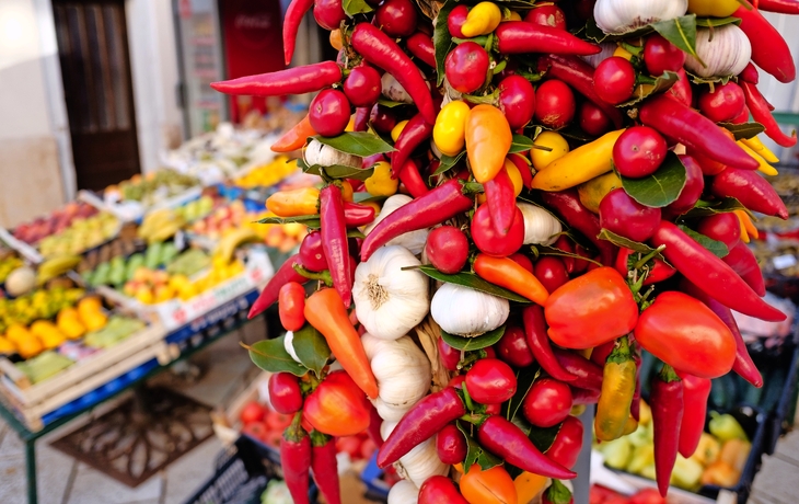 Bunte Chilischoten und Knoblauch an einem Marktstand. - © Neil Julian - stock.adobe.com