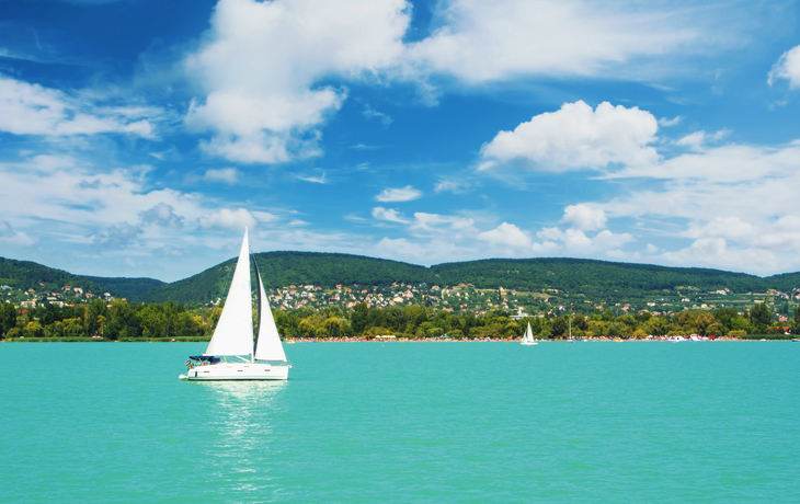 Luftaufnahme einer Kirche am Balaton-See mit umliegendem Dorf und blauem Himmel. - ©zgphotography - stock.adobe.com