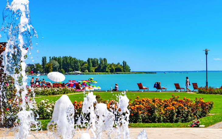 Luftaufnahme einer Kirche am Balaton-See mit umliegendem Dorf und blauem Himmel. - ©zgphotography - stock.adobe.com