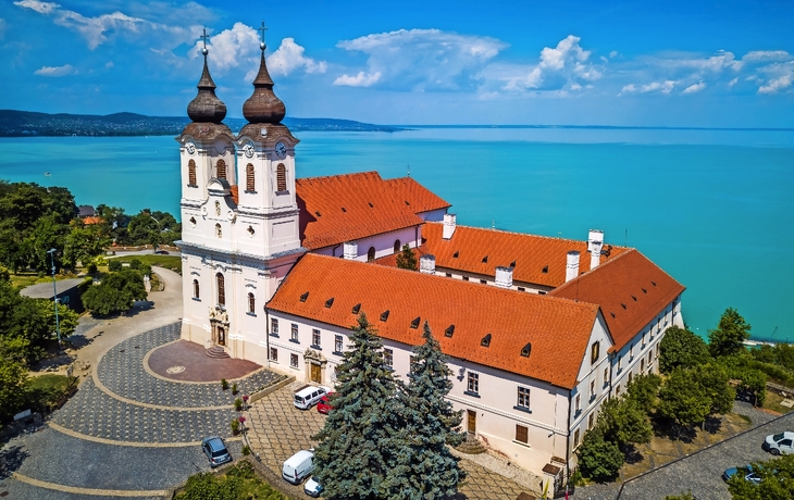 Luftaufnahme einer Kirche am Balaton-See mit umliegendem Dorf und blauem Himmel. - ©zgphotography - stock.adobe.com