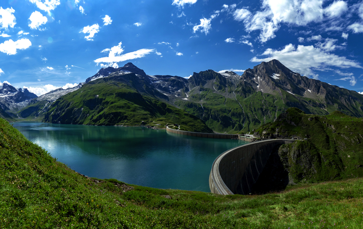 Staumauer in alpiner Landschaft mit See und schneebedeckten Bergen im Hintergrund. - © serkat Photography - stock.adobe.com