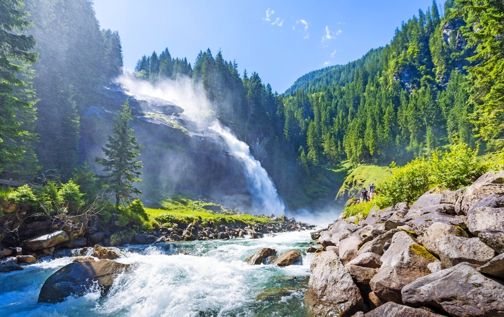Wasserfall in einem Waldgebiet unter blauem Himmel und Sonne. - © Comofoto - stock.adobe.com