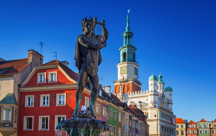 Statue eines Mannes mit Lyra vor bunten Gebäuden und einem Turm. - © Patryk Kosmider - stock.adobe.com