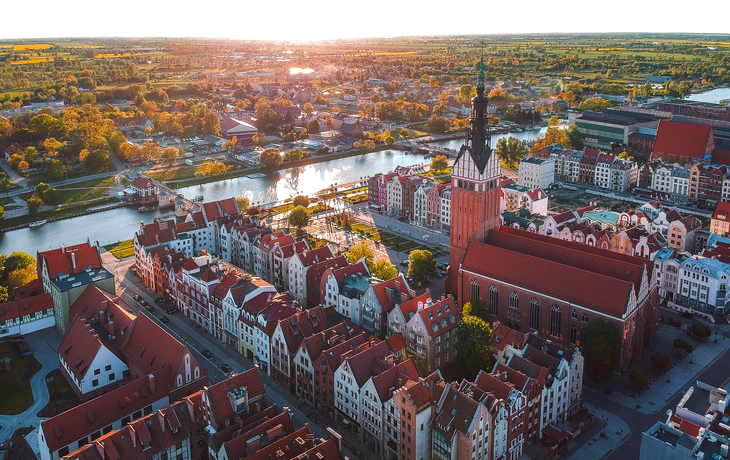 Stadtansicht mit Kirche und Fluss bei Sonnenuntergang aus der Vogelperspektive - © uslatar - stock.adobe.com