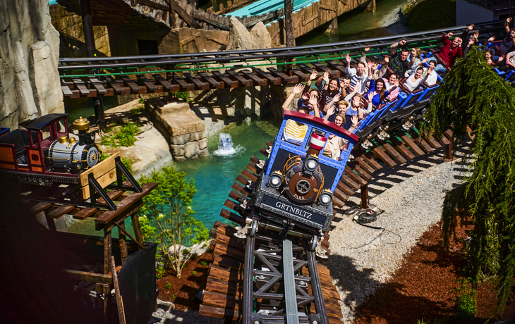 Achterbahn in einem Freizeitpark, voll besetzter Zug, sonniger Tag. - Europa-Park